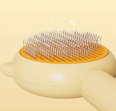 Pet grooming brush with orange base and white bristles on a beige background