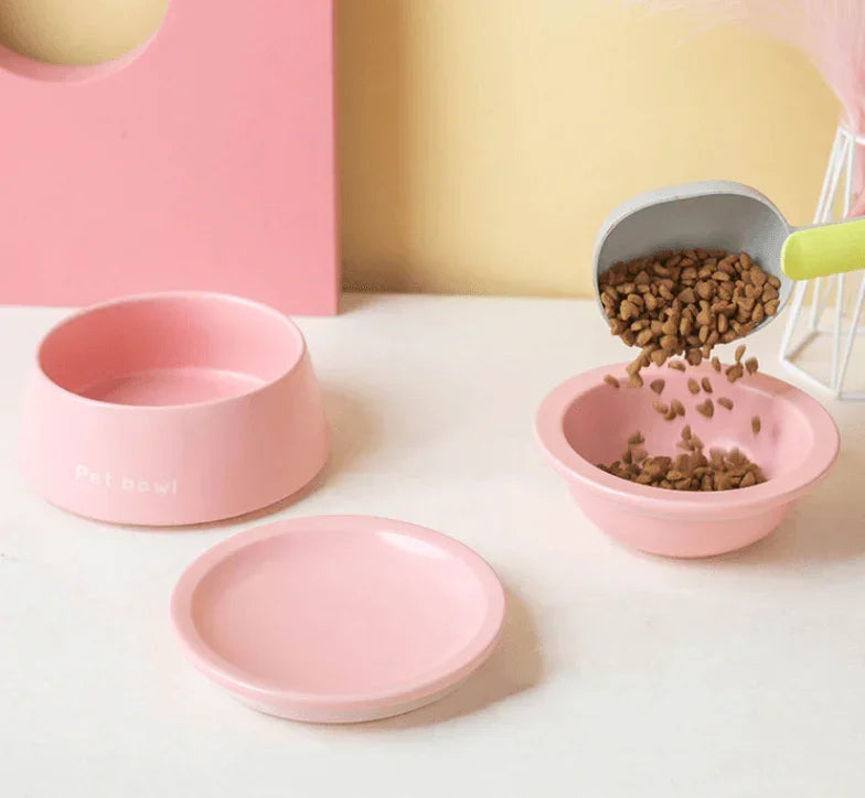 Pink pet bowls for cats and dogs with dry food being poured, stylish and practical pet supplies