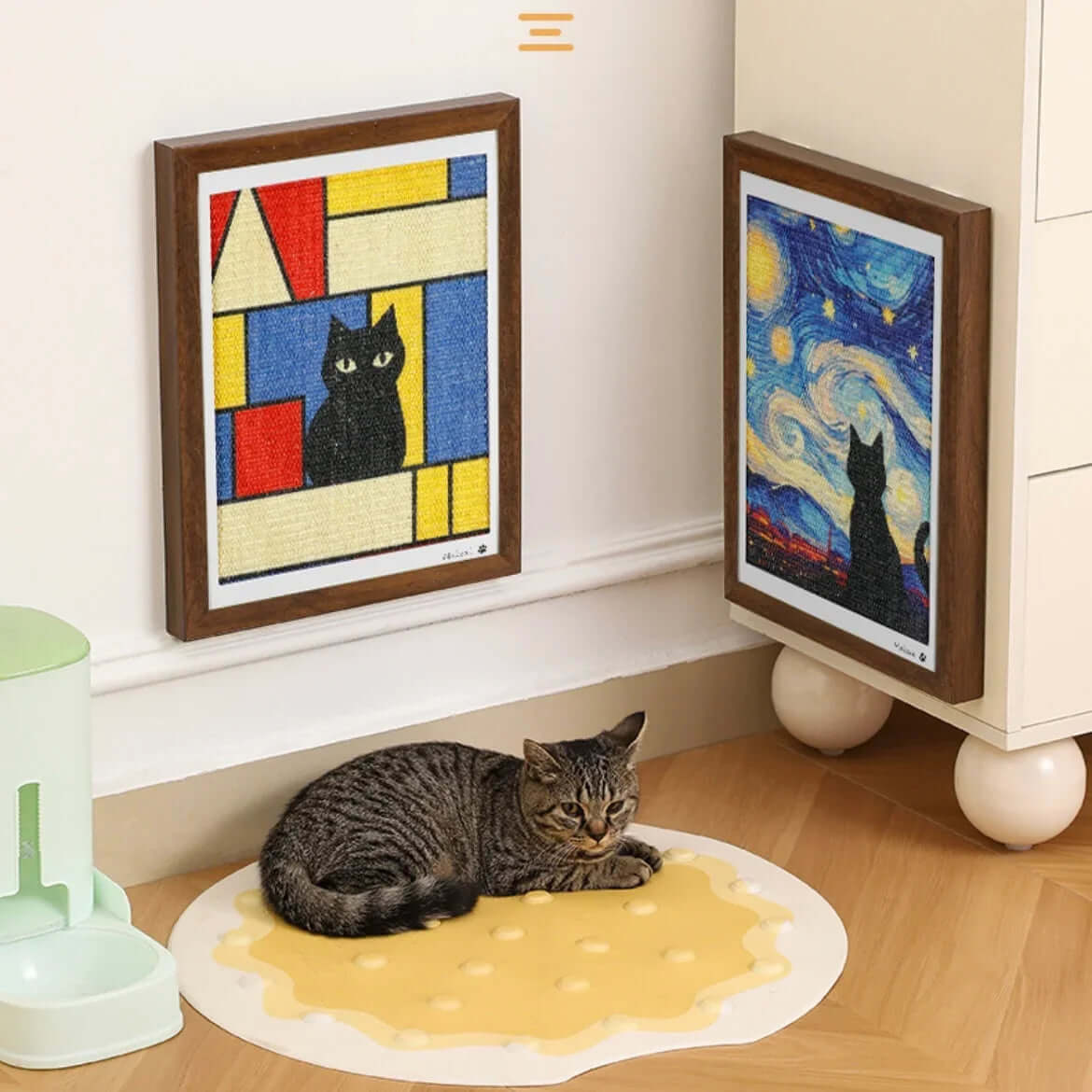 Tabby cat resting on pizza-shaped mat near cat-themed wall art, stylish pet decor for home
