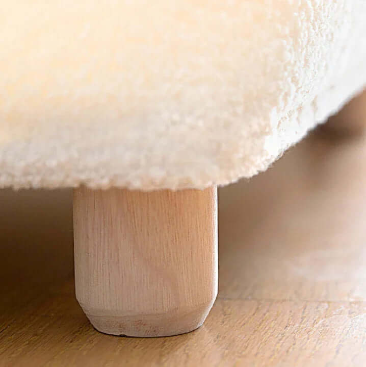 Close-up of a fluffy white cushion on a wooden stool.