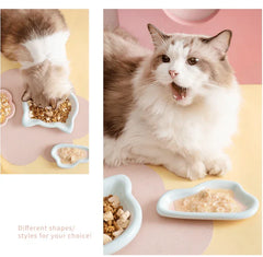 Fluffy cat eating from stylish ceramic bowls in pastel colors, perfect for cat food and treats.