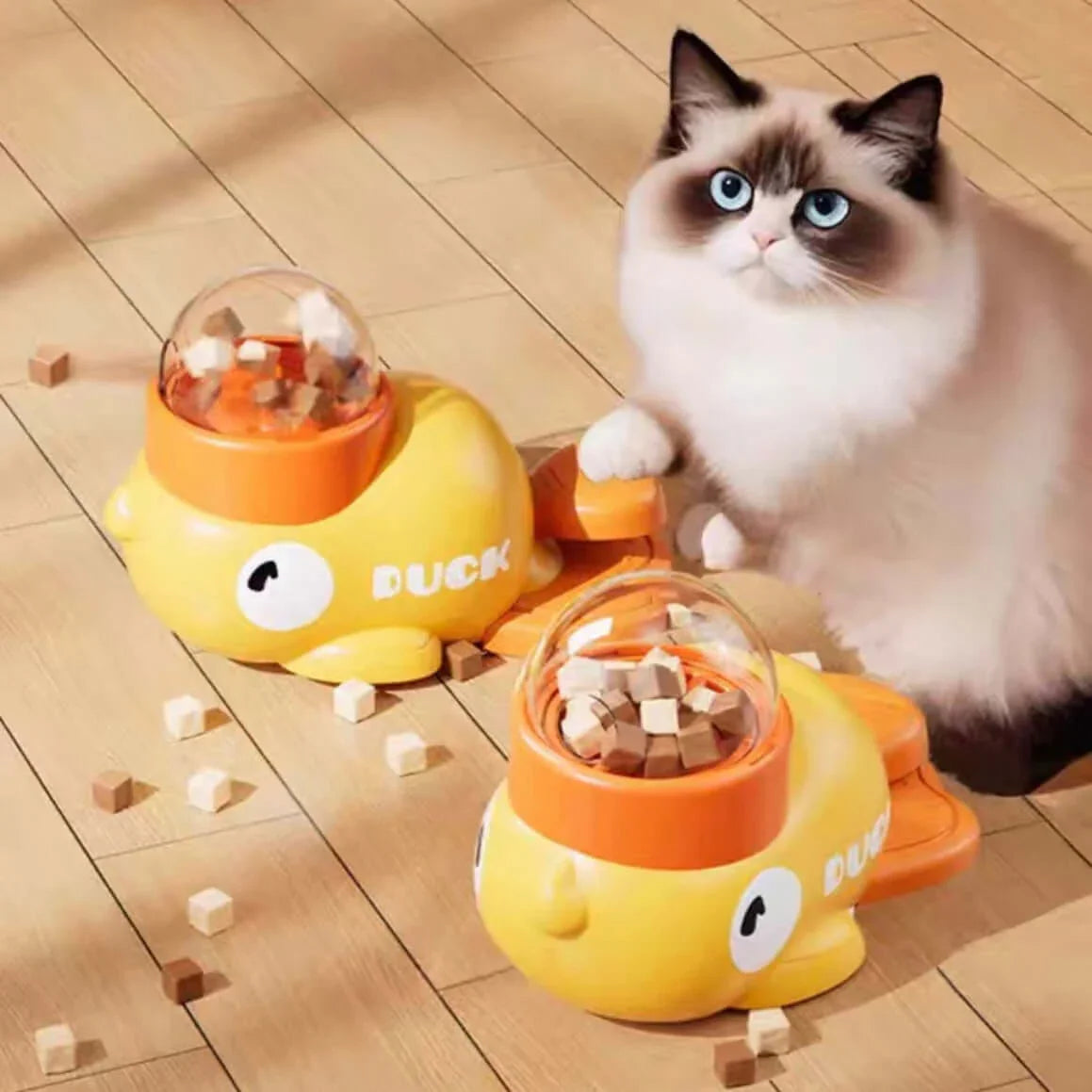 Fluffy cat playing with yellow duck-shaped interactive treat dispenser toys on wooden floor