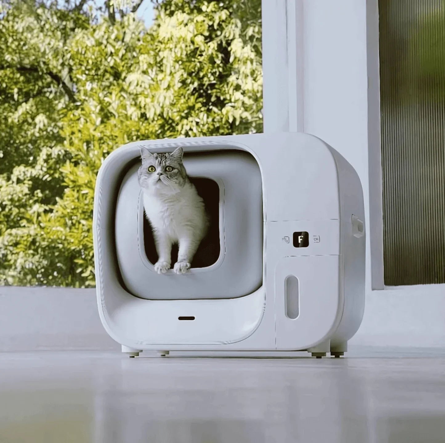 White automatic self-cleaning litter box with cat inside, modern pet supply for home