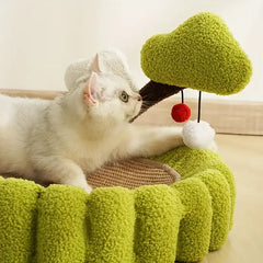 White cat playing with green plush tree toy in cozy pet bed, perfect for indoor cats and playful kittens
