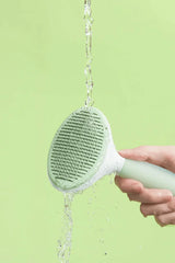 Water running over the Michu Round-Head Grooming Dog Cat Brush, showcasing its cleaning features.