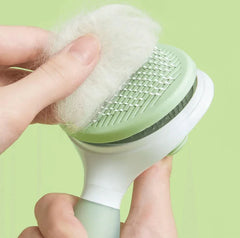 Hand holding the Michu Round-Head Grooming Dog Cat Brush with collected pet fur.