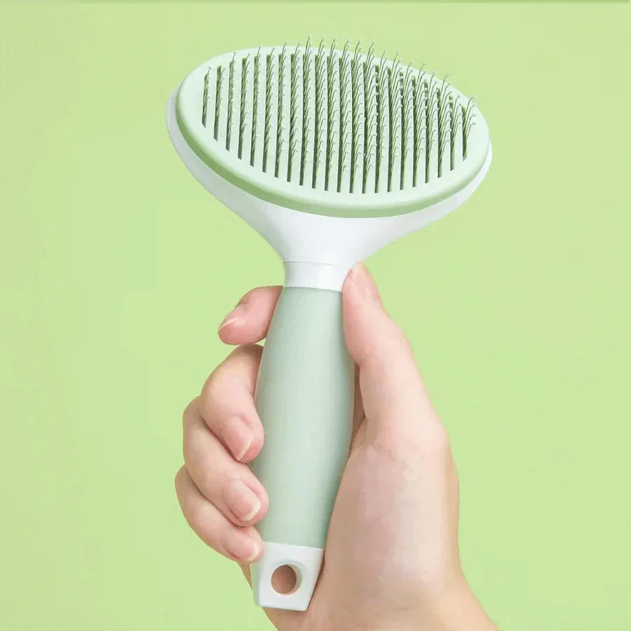 Michu Round-Head Grooming Dog/Cat Brush & Shedding Rake Bundle held in hand against a green background.
