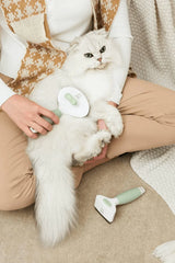 Michu Undercoat Grooming Tool Shedding Rake used by pet owner on a fluffy cat during grooming session.