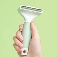 Michu Undercoat Grooming Tool Shedding Rake held in hand against a green background, perfect for pet grooming.