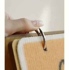 Hand attaching metal ring to pet mat with wooden frame, ideal for cat or dog accessories.