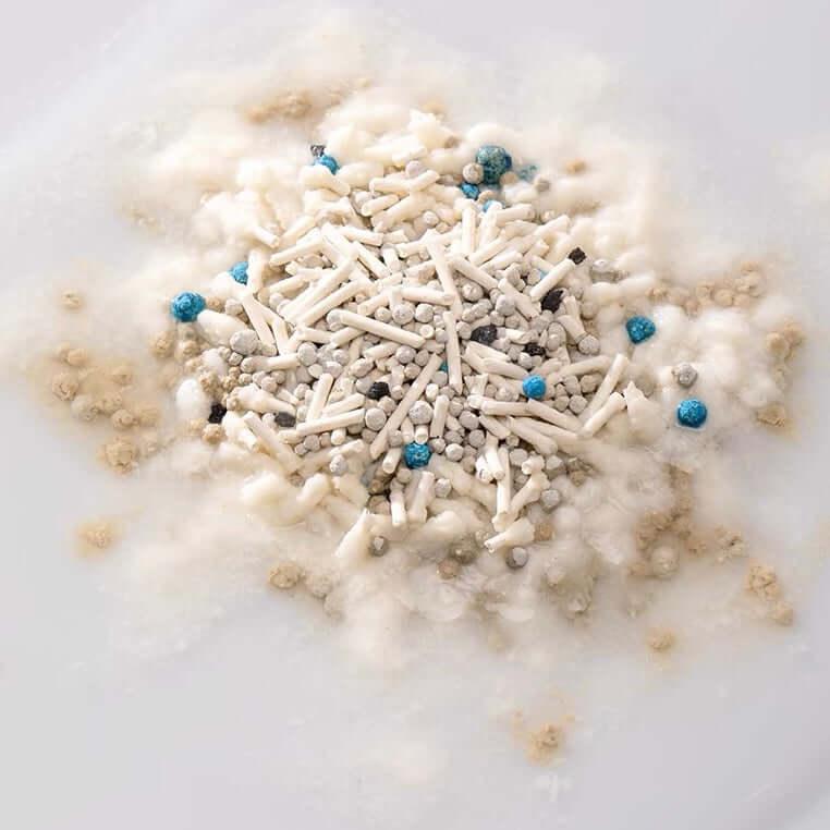 Clumping cat litter with blue odor-control beads and white granules for effective pet waste management