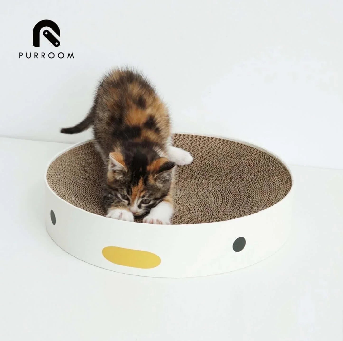 Calico kitten playing in a round cardboard scratcher with cute face design, ideal cat toy and pet supply.