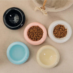 Stylish ceramic pet bowls in black, pink, white, blue, and cream, filled with dry food and water for cats and dogs.