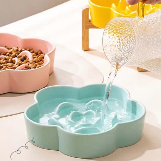 Flower-shaped pet water bowl being filled, with pink food bowl nearby — stylish cat & dog supplies