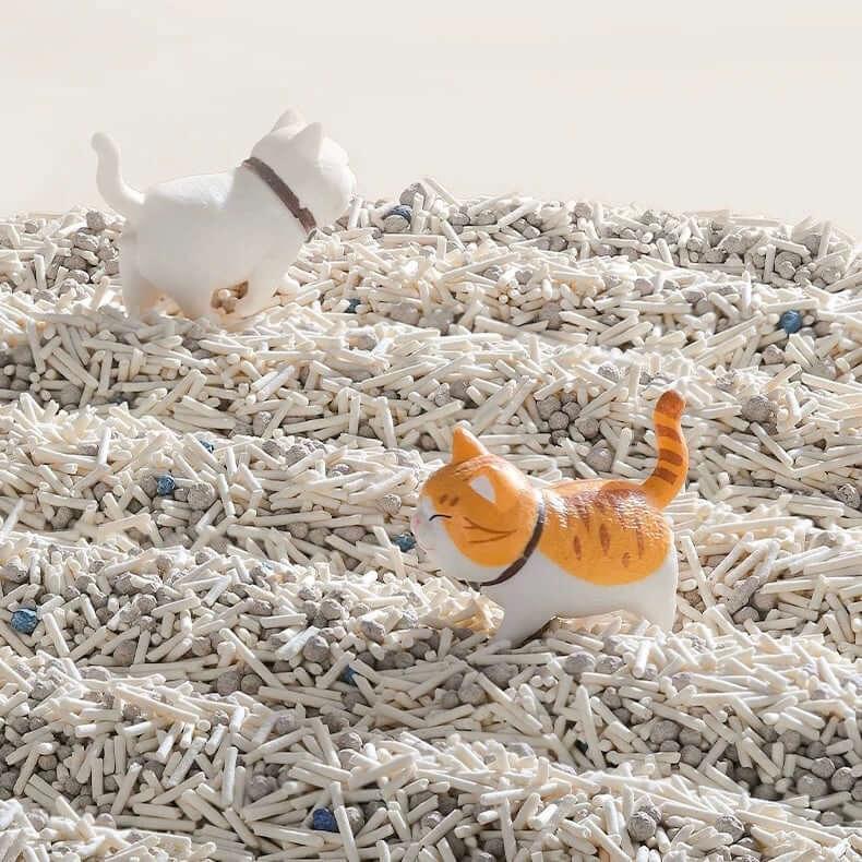 Cute cat figurines playing in clumping cat litter, perfect for pet owners seeking stylish pet supplies.