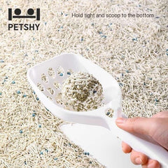 White cat litter scoop holding clumped litter in a litter box, ideal for easy cleaning and pet care.