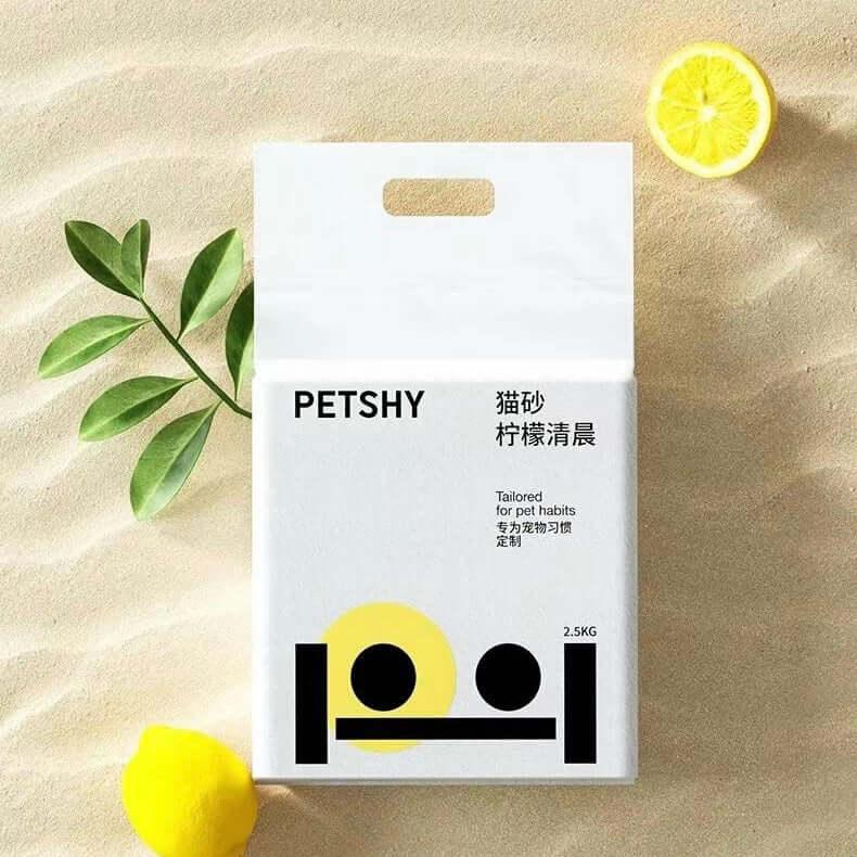 PETSHY lemon-scented cat litter 2.5kg, styled with fresh lemon slices and green leaves on sandy background