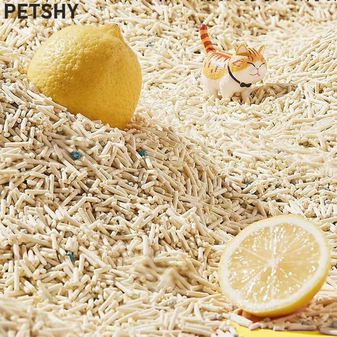 Lemon-scented cat litter with toy cat and fresh lemons, ideal for odor control and pet hygiene.