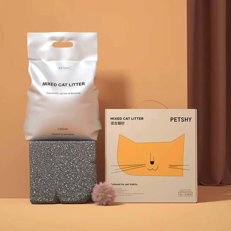 Mixed cat litter bag and box with gray granules, fluffy pom-pom, and orange cat graphic for pet care.