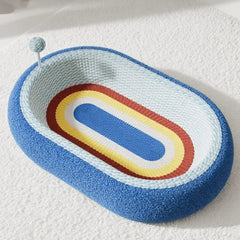 Colorful oval pet bed with blue, red, yellow stripes and yarn ball toy, cozy for cats or dogs