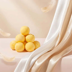 PawDry Freeze-Dried Quail Egg Yolk 100g pyramid display with soft silk drapery and feathers.