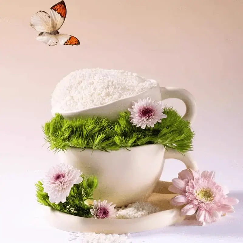 White ceramic cup filled with rice, green grass, and pink flowers, with butterfly flying nearby