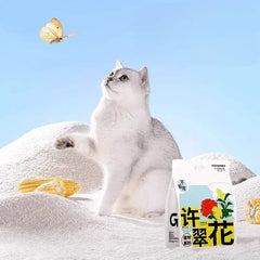 White cat playing with butterfly beside plant-based cat litter bag and corn cobs on white sand