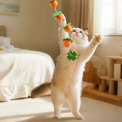 Fluffy white cat playing with orange felt toy in cozy bedroom
