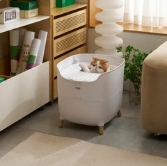 Orange cat relaxing in modern white litter box with wooden legs, stylish pet supply for home