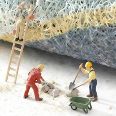 Miniature figurines working on a textured surface, depicting a construction scene with a ladder and wheelbarrow.