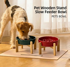 Dog eating from elevated wooden slow feeder bowl, red and green pet bowls on stand for healthy feeding