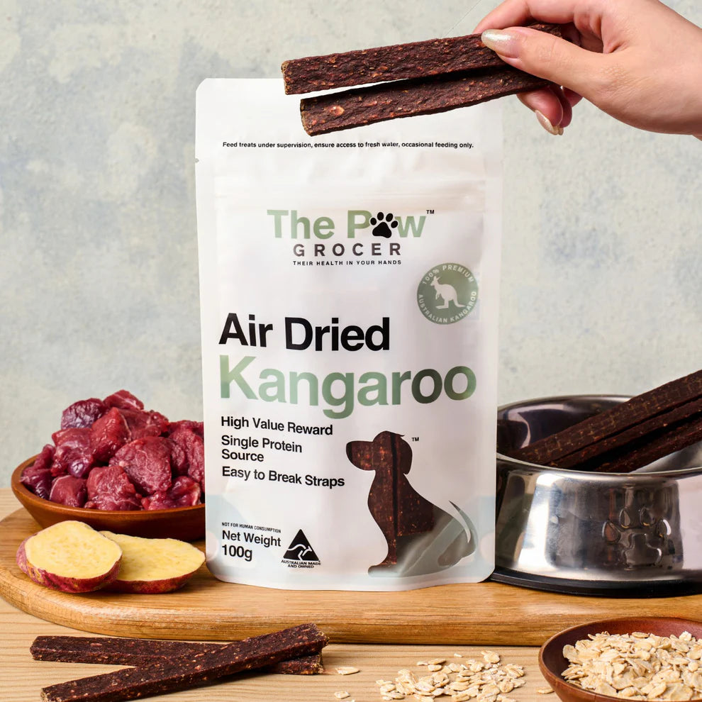 THE PAW GROCER Air-Dried Kangaroo Dog Training Straps 100g packaging with training straps on a wooden table.