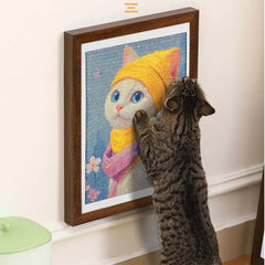 Tabby cat pawing at framed cat portrait with yellow hat, pet wall art for cat lovers