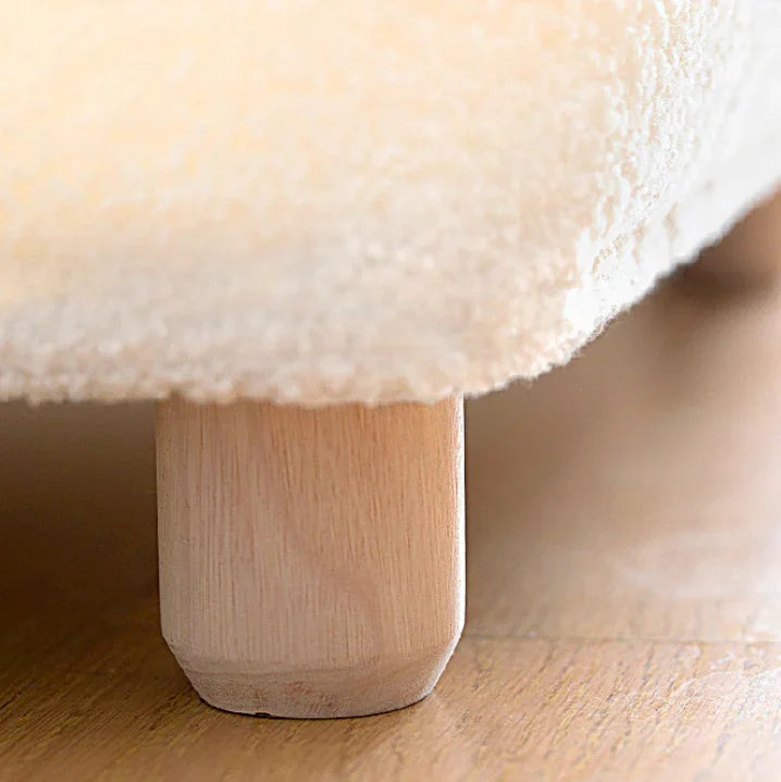 Close-up of a fluffy white cushion on a wooden stool.