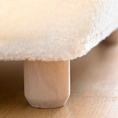 Close-up of a fluffy white cushion on a wooden stool.