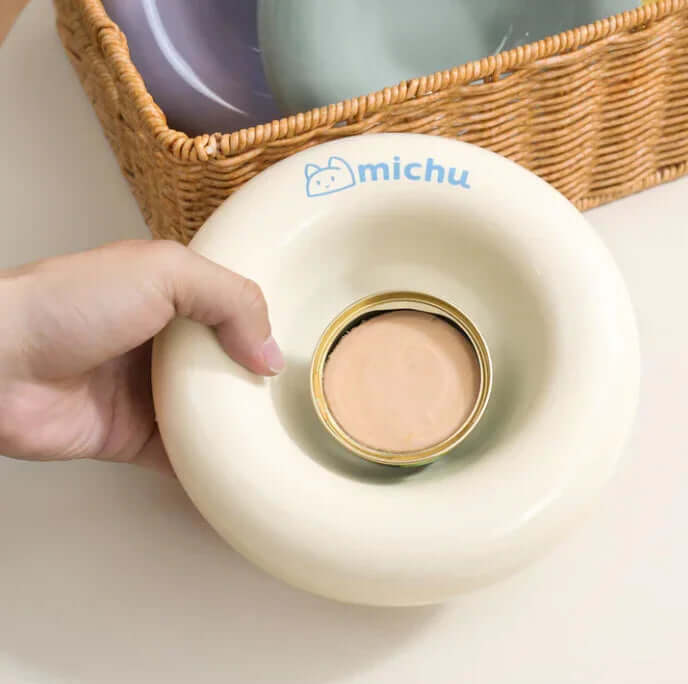 Michu Ceramic Cat Bagel Bowl – Anti-Whisker Wide Shallow Pet Food Bowl Rainbow Colours in hand with a basket in background.