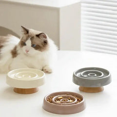 Stylish slow feed cat bowls in cream, grey, and terracotta with wooden bases, ideal for healthy pet feeding.
