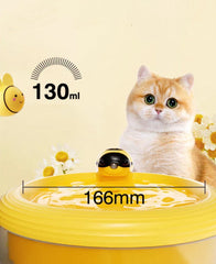 A yellow duck-shaped pet waterer shown with a cat behind it and overlaid size/measurement graphics reading 130ml and 166mm. The scene includes decorative flowers and a pale cream background.