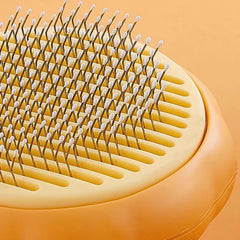Close-up of a yellow pet grooming brush with metal pins on an orange background