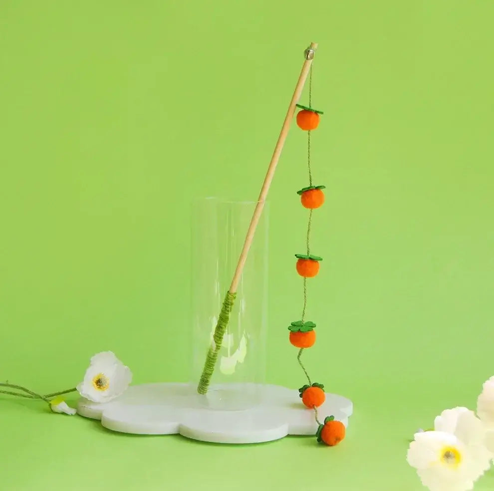 Cat wand toy with orange pom-pom fruits on green string, perfect for playful cats and interactive pet play.