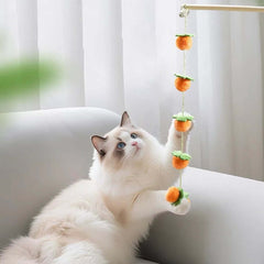 Fluffy cat playing with orange pom-pom hanging toy on white sofa